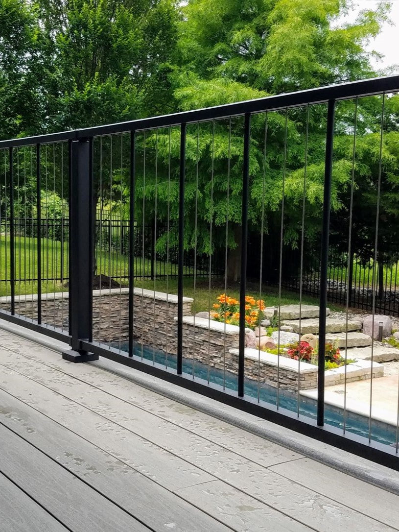 C80 Verticable Level cable rail vertical by westbury in fine texture black by westbury set infront of a pool with lush green all around c80 vertical cable complements and looks wonderful as well as alows for non-obstructed view beyond railing