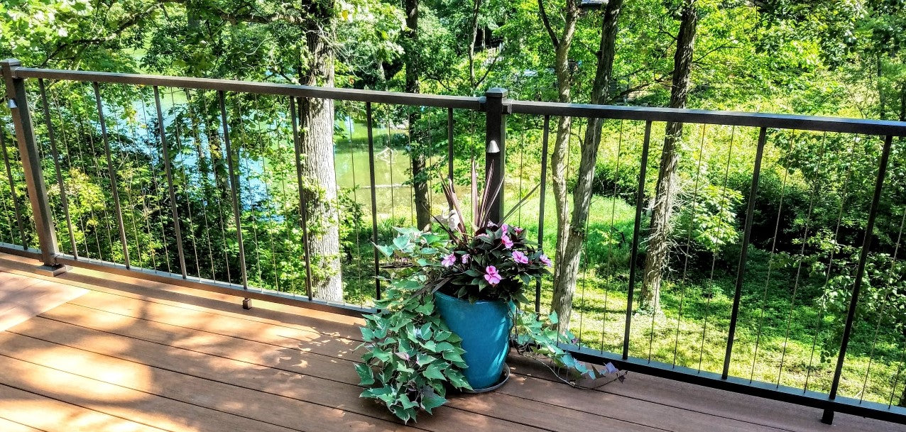 Westbury C-80 Vertical Cable Railing VertiCable on a beautiful lake front property with green folleage and a flower in a pot